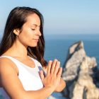 A woman meditates peacefully by the ocean in Portugal, embracing wellness.