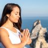 A woman meditates peacefully by the ocean in Portugal, embracing wellness.