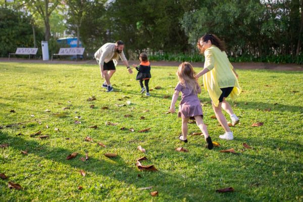 A joyful family playing together in a lush green park setting, enjoying a bright day.