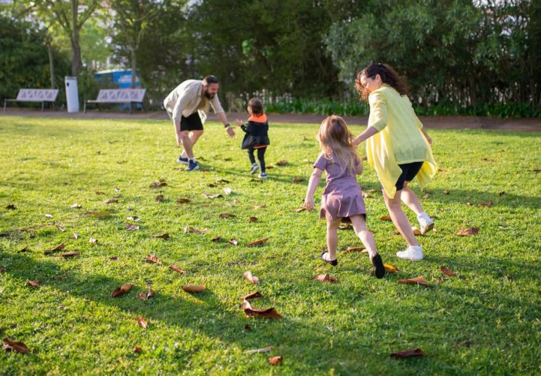 A joyful family playing together in a lush green park setting, enjoying a bright day.