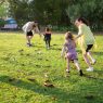 A joyful family playing together in a lush green park setting, enjoying a bright day.