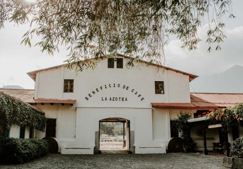 Charming historic building of Beneficio de Cafe La Azotea surrounded by lush greenery and cobblestones.