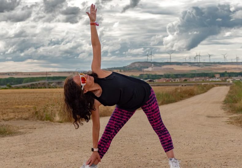 Outdoor fitness scene of a woman stretching on a dirt path in Soto de Cerrato amidst scenic landscapes.